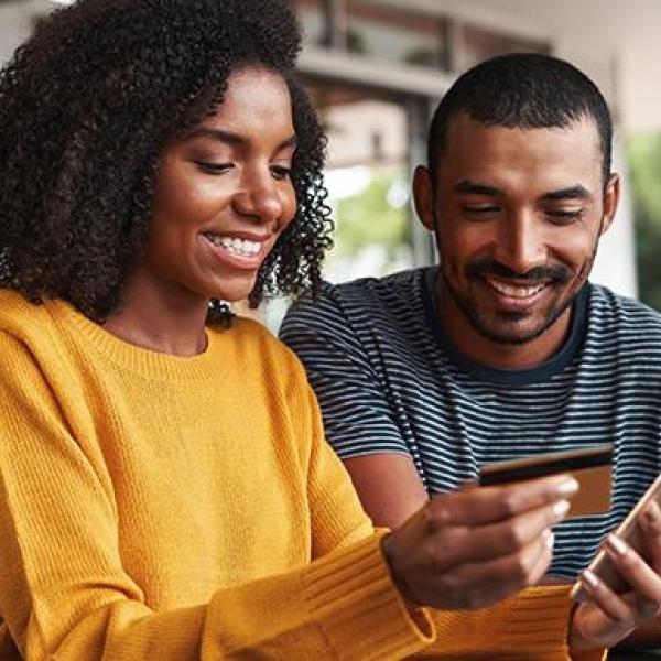 Couple avec téléphone et carte bancaire avec le sourire mutuelle